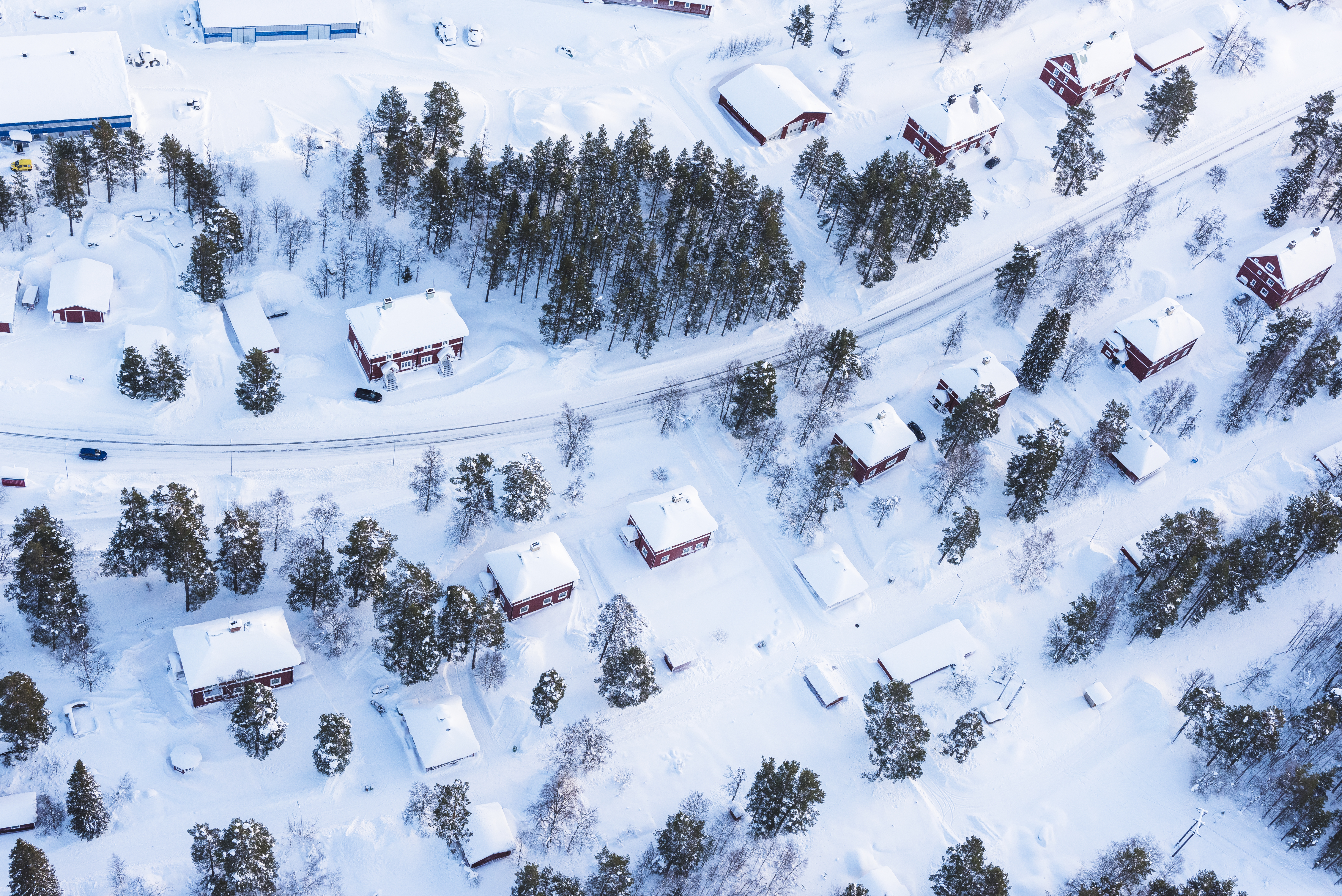 Snötäckt landskap med väg och hus.