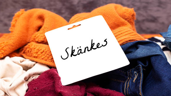 Klädhög med "Skänkes" lapp på toppen.